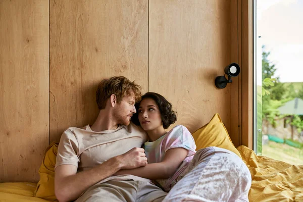 Interrassische Paar mit zärtlichen Moment, während sie zusammen auf dem Bett liegen und einander anschauen — Stockfoto