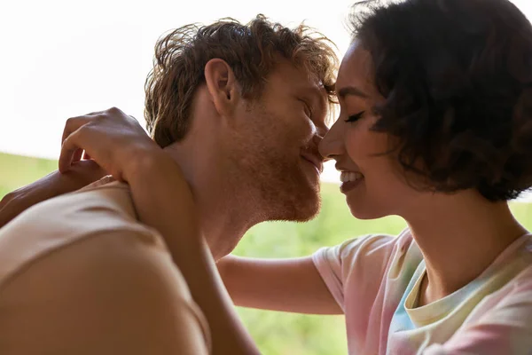 Vue rapprochée du couple interracial heureux embrasser et sourire à la maison, coller et tendresse — Photo de stock