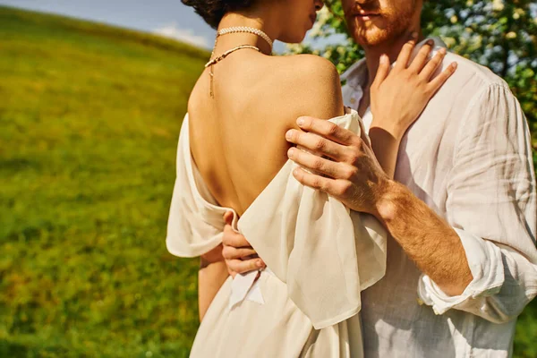 Vue recadrée de couple sensuel de jeunes mariés s'embrassant dans le jardin vert, mariage rural — Photo de stock