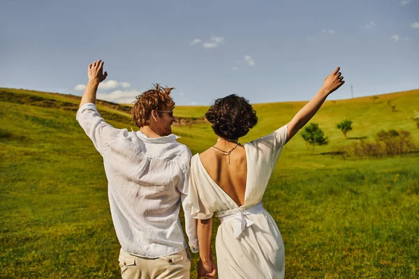 Rural wedding, bride in wedding dress holding hands with happy groom in field, just married couple — Stock Photo