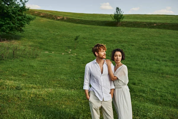 Apenas casado casal interracial de pé juntos no campo verde, paisagem cênica e tranquila — Fotografia de Stock