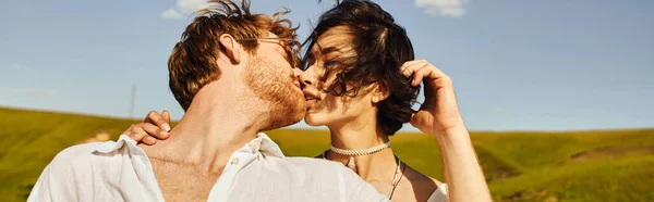 Mariage rustique, jeune interracial jeunes mariés embrassant sur le vent sous le ciel bleu dans le champ vert, bannière — Photo de stock