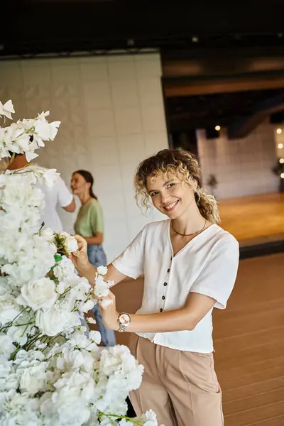 Equipe de decoradores criativos organizando decoração floral no moderno salão de eventos espaçoso, design festivo — Fotografia de Stock