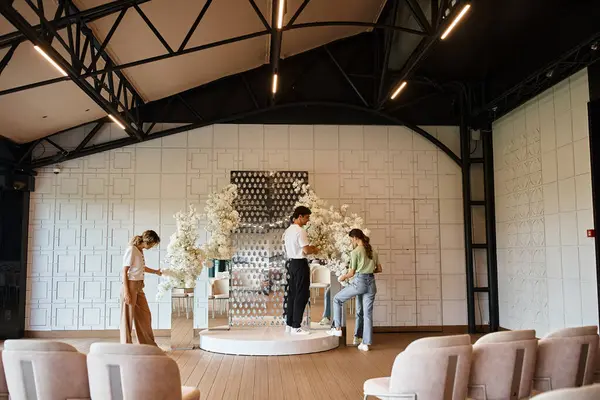 Kreatives Team von Eventdesignern bereitet moderne Festhalle vor, indem es florale Kompositionen arrangiert — Stockfoto