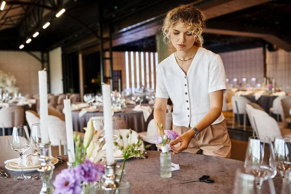 Blondine arrangiert festliche Tischdekoration mit Kerzen und Blumen, kreative Eventdekorateurin — Stockfoto