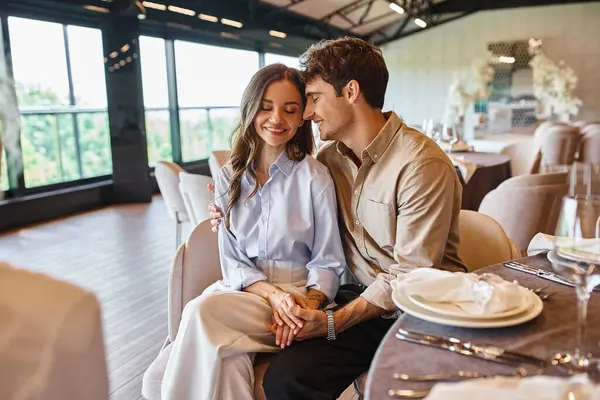 Delighted couple in love smiling with closed eyes near event manager in modern wedding hall — Stock Photo