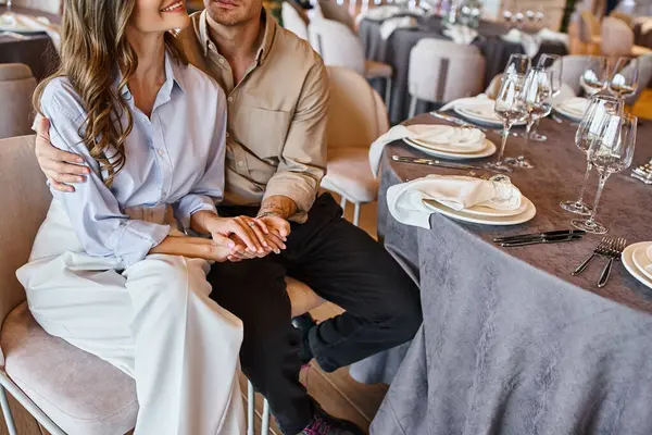 Обрізаний вид на емальовану пару, що сидить за святковим столом у банкетному залі, підготовка весілля — стокове фото