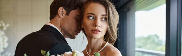 Joven hermosa novia mirando lejos cerca del novio en traje negro en salón de banquetes, día especial, pancarta - foto de stock