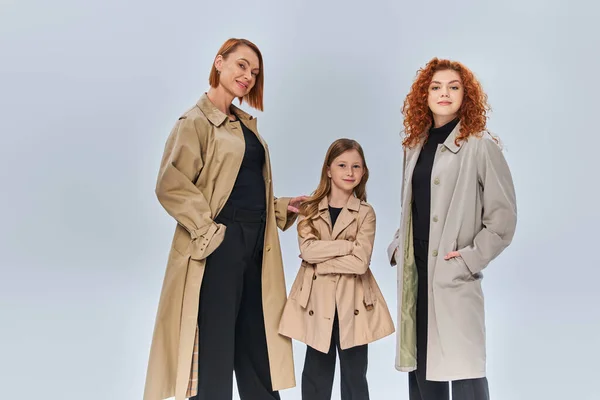 Famille de rousses de trois générations posant ensemble en manteaux d'automne sur fond gris, à la mode automne — Photo de stock