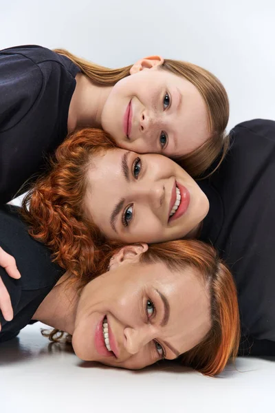 Three generations concept, happy women and girl smiling and looking at camera on grey backdrop — Stock Photo