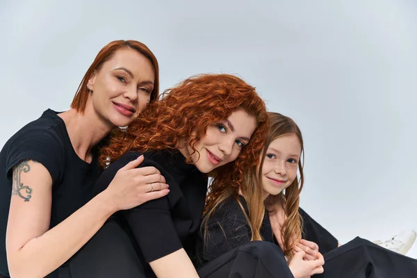 Three generations concept, cheerful redhead family smiling and looking at camera on grey backdrop — Stock Photo