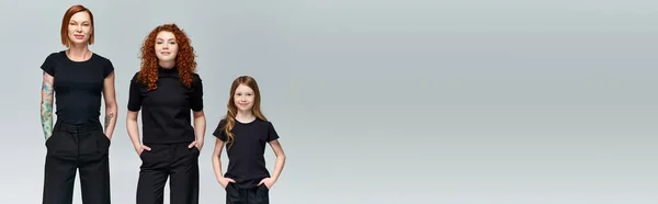 Покоління, щаслива сім'я позує руками в кишенях у відповідному вбранні на сірому тлі, банер — стокове фото