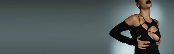 Обрізаний вид стильної спокусливої жінки в чорному костюмі на Хеллоуїн на сірій, готичній красуні, банер — стокове фото