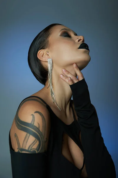 Спокуслива жінка з моторошним макіяжем, торкаючись шиї на синьому і сірому тлі, концепція Хеллоуїна — стокове фото