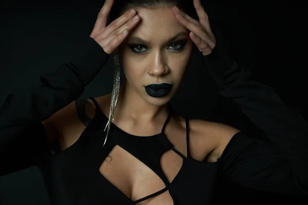 Дьявольская красота, женщина в сексуальном платье Хэллоуина и темный макияж глядя на камеру на черном, портрет — стоковое фото