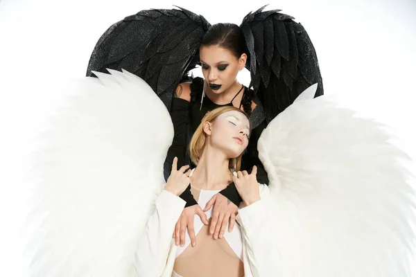 Темный падший ангел искушает светлое крылатое существо на белом, библейском представлении добра против зла — стоковое фото