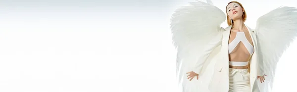 Hermosa mujer angelical en traje de Halloween con alas celestiales posando en blanco, bandera - foto de stock