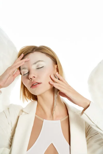 Graceful woman in costume of winged angel posing with closed eyes and hands near face on white — Stock Photo