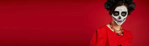 Portrait de femme effrayante dans le maquillage traditionnel dia de los muertos et perles colorées sur rouge, bannière — Photo de stock