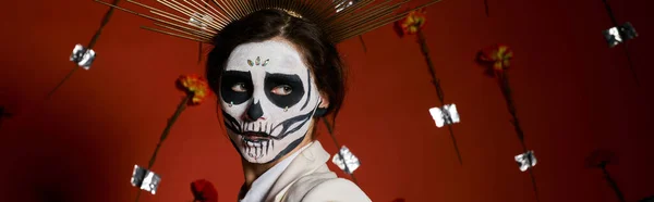 Mujer aterradora en día de los muertos maquillaje de cráneo de azúcar mirando hacia otro lado sobre fondo floral rojo, pancarta - foto de stock