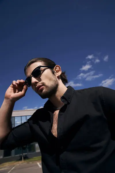 Vertical shot of good looking bearded man with sunglasses and ponytail posing outdoors, sexy driver — Stock Photo