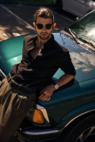 Beau modèle masculin élégant en tenue noire avec des lunettes de soleil posant et regardant la caméra, la mode — Photo de stock