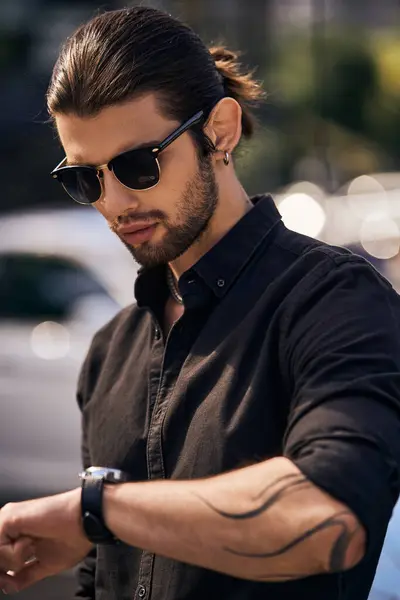 Plan vertical de beau modèle masculin dans une élégante tenue noire en regardant sa montre-bracelet, mode — Photo de stock