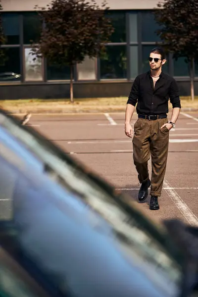 Gut aussehende junge männliche Modell in schwarzer lebendiger Kleidung zu Fuß zu seinem Auto mit der Hand in der Tasche, Mode — Stockfoto