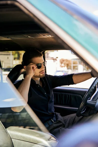 Gut aussehender Mann entspannt sich hinter dem Lenkrad seines Autos und berührt Sonnenbrille, sexy Fahrer — Stockfoto