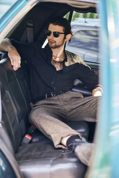 Vertikale Aufnahme eines entspannten Mannes in schwarzer eleganter Kleidung, der hinter dem Lenkrad chillt, sexy Fahrer — Stockfoto