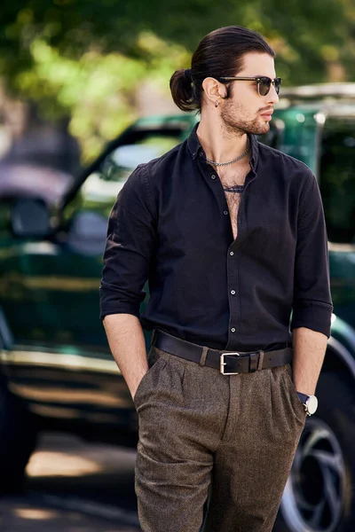 Plan vertical de jeune homme sexy avec des accessoires avec les mains dans les poches posant devant sa voiture — Photo de stock