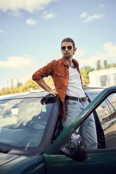 Vertical shot of appealing young man with sunglasses in brown shirt looking at camera, fashion — Stock Photo