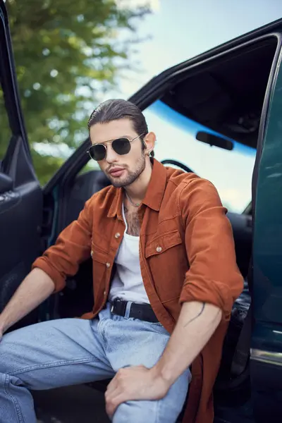Stylish handsome man with sunglasses and ponytail looking at camera and smiling slightly, style — Stock Photo