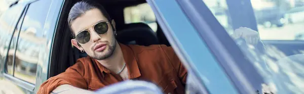 Bel homme élégant en chemise marron regardant par la fenêtre de la voiture, concept de mode, bannière — Photo de stock