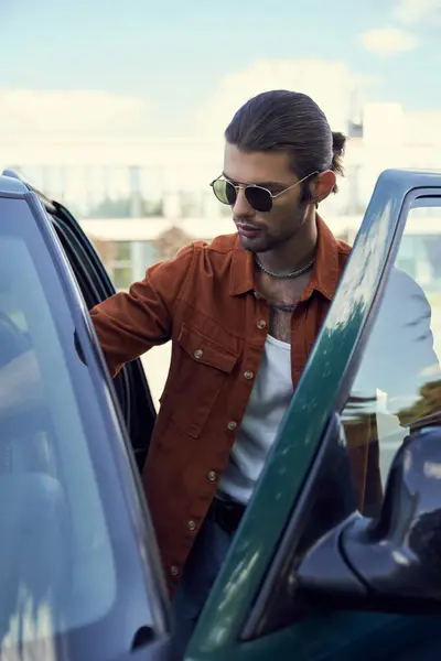 Vertikale Aufnahme eines jungen attraktiven Mannes in stylischem Outfit mit Sonnenbrille, der ins Auto steigt, Mode — Stockfoto