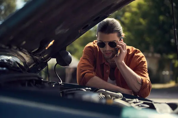 Stylish driver in elegant attire calling his insurer and looking at opened engine hood of his car — Stock Photo