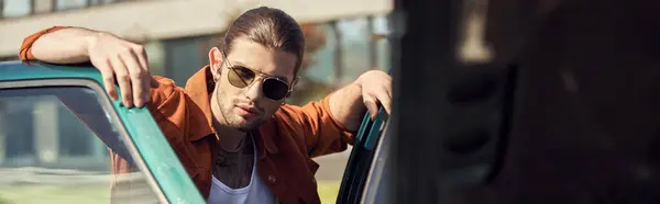 Good looking sexy driver in brown shirt with sunglasses looking at camera next to his car, banner — Stock Photo