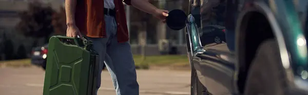 Vista ritagliata del giovane in camicia marrone elegante con jeans rifornimento della sua auto con benzina, banner — Foto stock