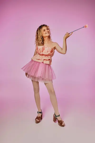 Bella donna sorridente posa in costume fatina dei denti con bacchetta magica posa su sfondo rosa — Foto stock