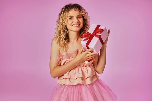 Красивая блондинка в розовом костюме зубной феи улыбается в камеру и держит подарок — стоковое фото