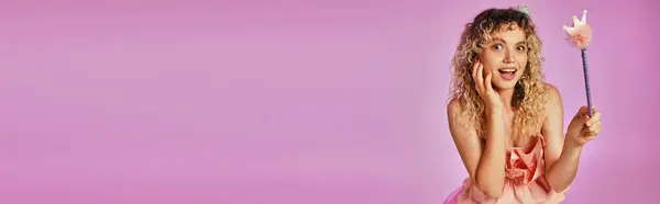 Слегка шокирована радостная женщина в костюме зубной феи держа волшебную палочку на розовом фоне, баннер — стоковое фото