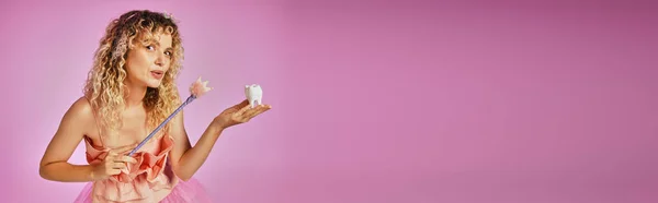 Séduisante belle femme en costume de fée de dents roses jetant de façon ludique sort sur la dent de bébé, bannière — Photo de stock