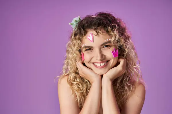 Portrait of attractive woman in pink costume with face stickers looking cheerfully at camera — Stock Photo