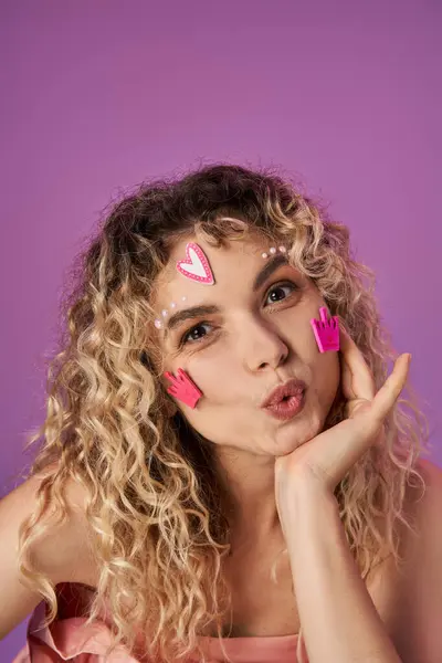 Attractive blonde woman with curly hair and bright face stickers expressing astonishment at camera — Stock Photo