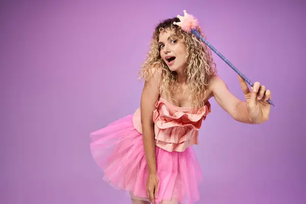 Вражена жінка в костюмі рожевого зуба з чарівною паличкою в руці заклинання і дивиться на камеру — стокове фото