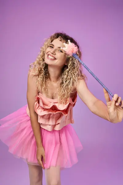 Веселая привлекательная женщина с вьющимися волосами в костюме зубной феи с волшебной палочкой, смотрящая в камеру — стоковое фото
