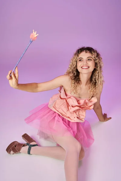 Attraktive Frau in rosafarbenem, lebendigem Kleid auf dem Boden sitzend mit Zauberstab, Zahnfee-Konzept — Stockfoto