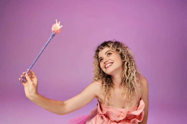 Мечтательная привлекательная женщина в розовом платье держа волшебную палочку и глядя в сторону, концепция зубной феи — стоковое фото