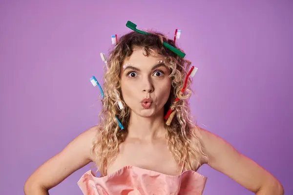 Astonished blonde woman in pink vibrant outfit and toothbrushes in her hair, tooth fairy concept — Stock Photo