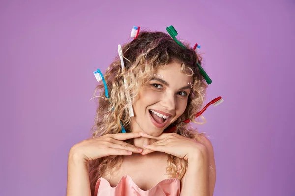 Lovely attractive tooth fairy with toothbrushes in her curly hair smiling cheerfully at camera — Stock Photo